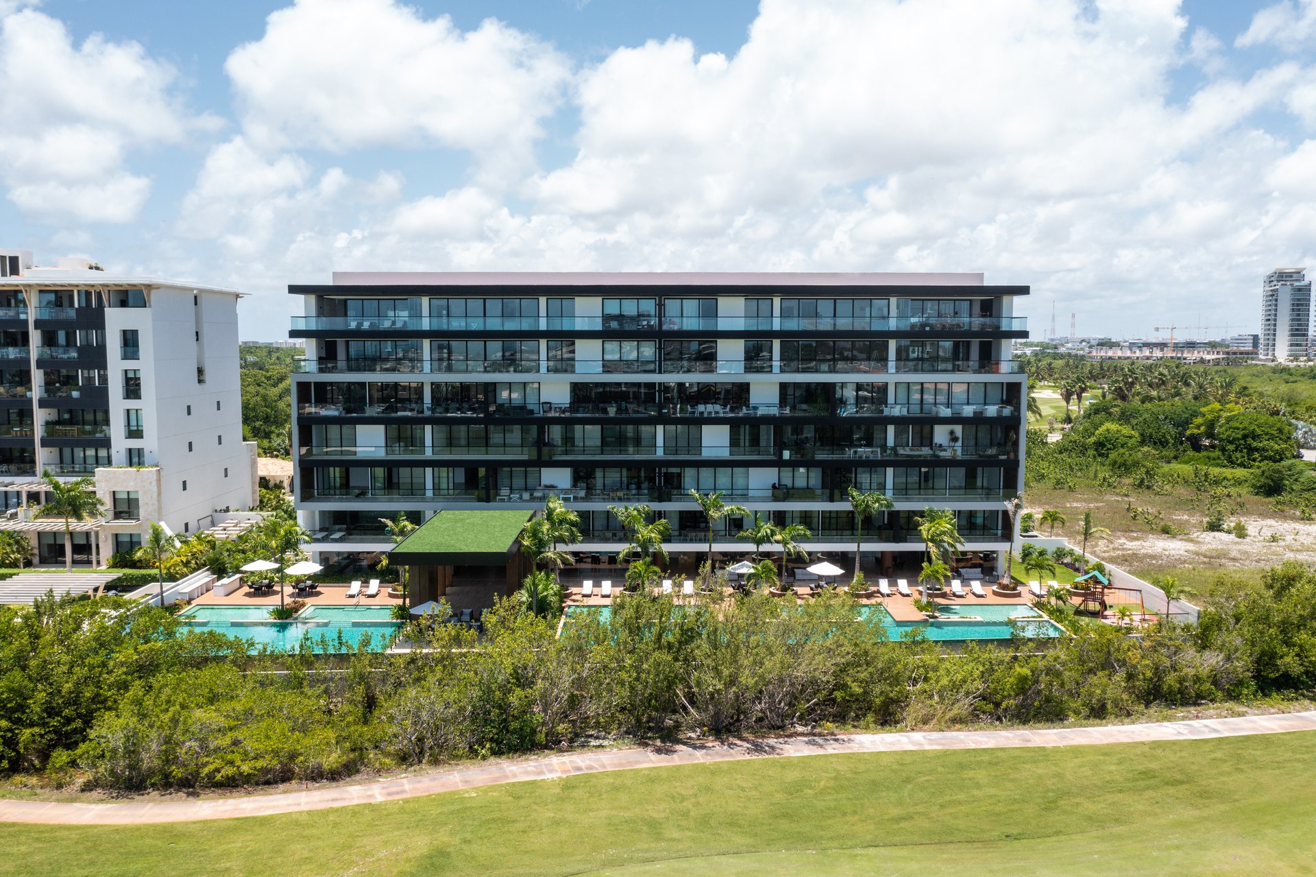 Antaal, en Puerto Cancún, diseñado por Arkham Projects: las dos torres sobre el jardín central y la alberca, con el manglar detrás