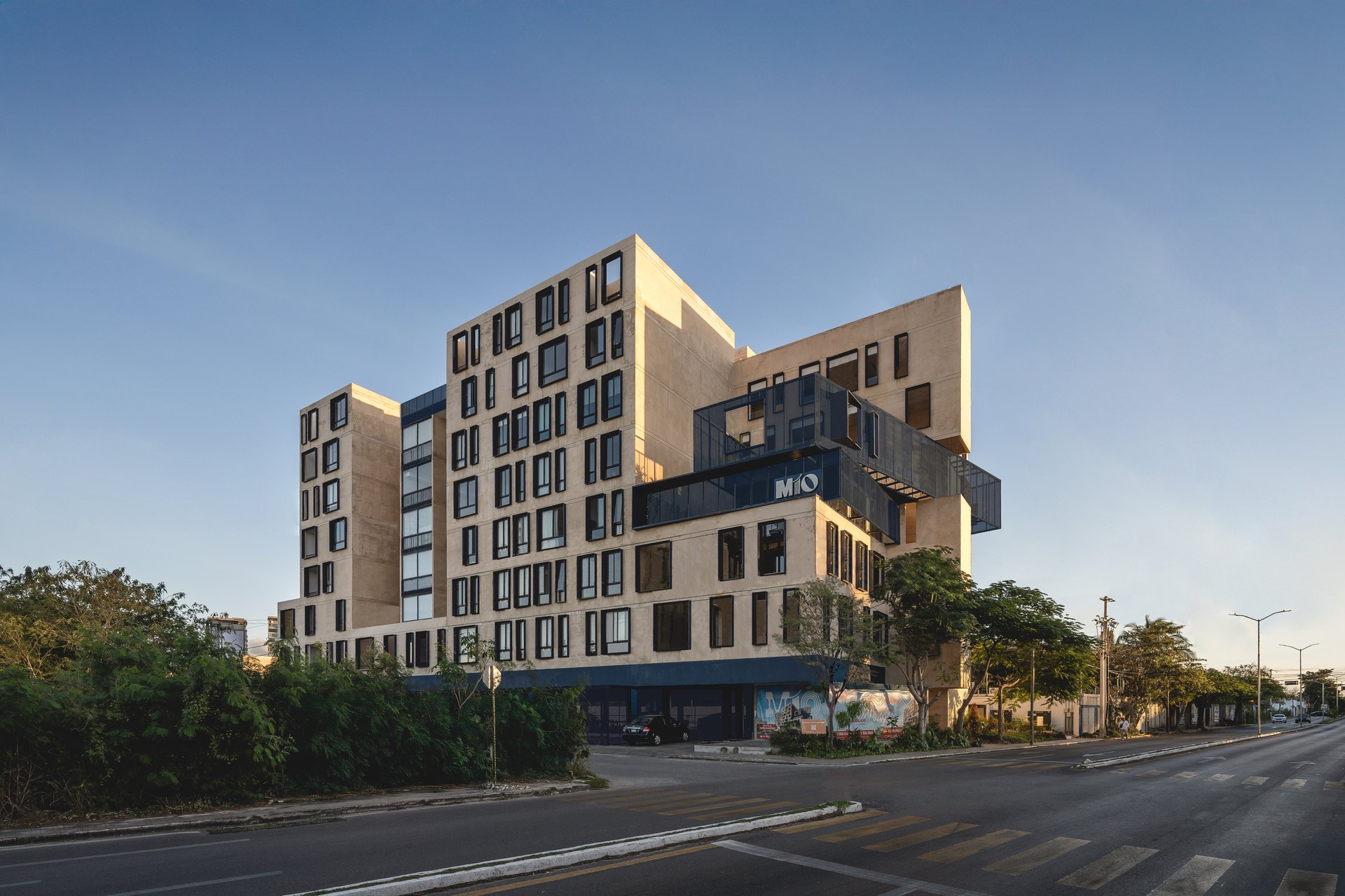 Mio Montebello, edificio de departamentos diseñado por Arkham Projects: la fachada escalonada en esquina, con balcones y terrazas, al atardecer